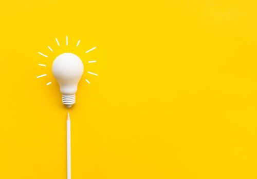 A white lightbulb with lines around it against a yellow background.
