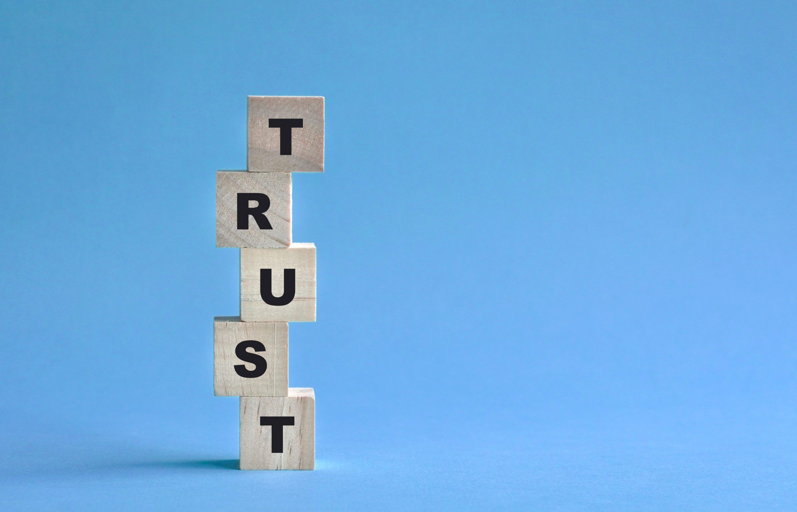 Building trust online: wooden building blocks that spell trust. The blocks are stacked on top of each other